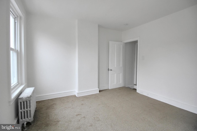 spare room with plenty of natural light, carpet flooring, and radiator