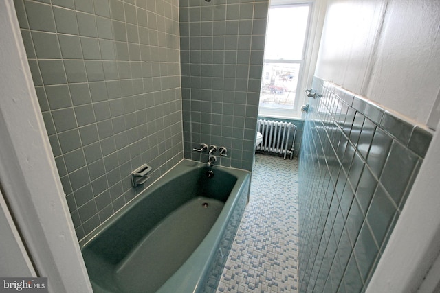 bathroom with toilet, radiator, tile walls, and tiled shower / bath combo