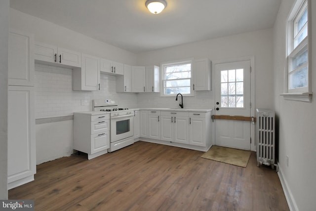 kitchen with sink, white cabinetry, radiator, white range with gas cooktop, and dark hardwood / wood-style floors