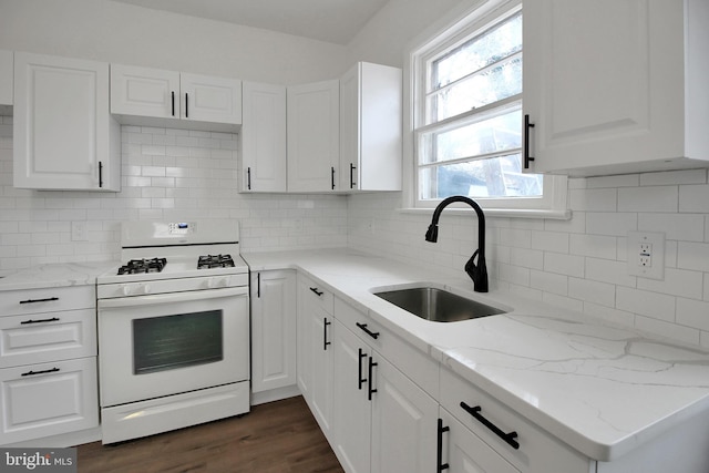 kitchen featuring sink, gas range gas stove, white cabinets, and tasteful backsplash