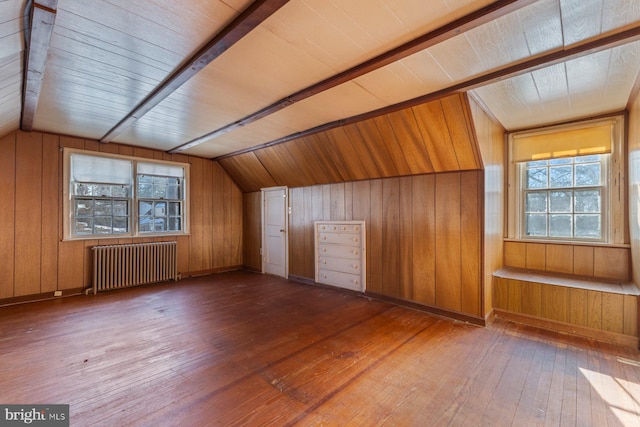 additional living space with vaulted ceiling, radiator, hardwood / wood-style floors, and wooden walls