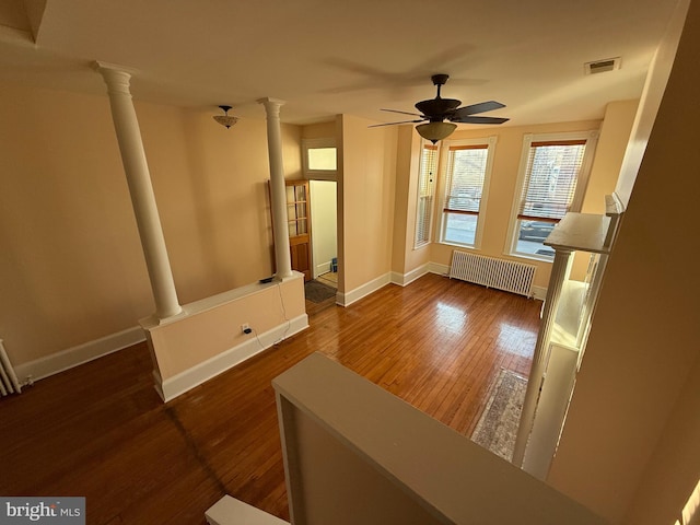 living room with radiator heating unit, dark hardwood / wood-style floors, ceiling fan, and ornate columns