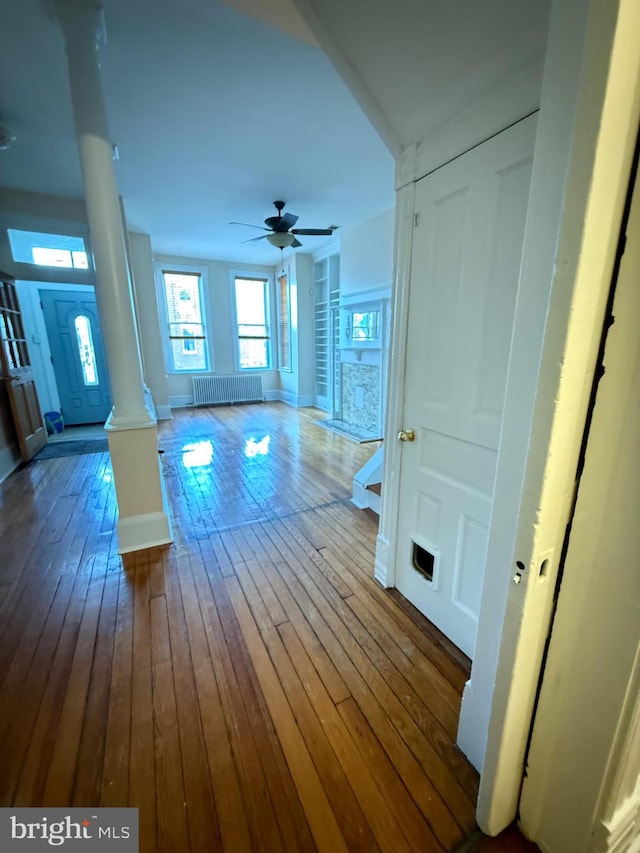 interior space with radiator, hardwood / wood-style floors, and ornate columns