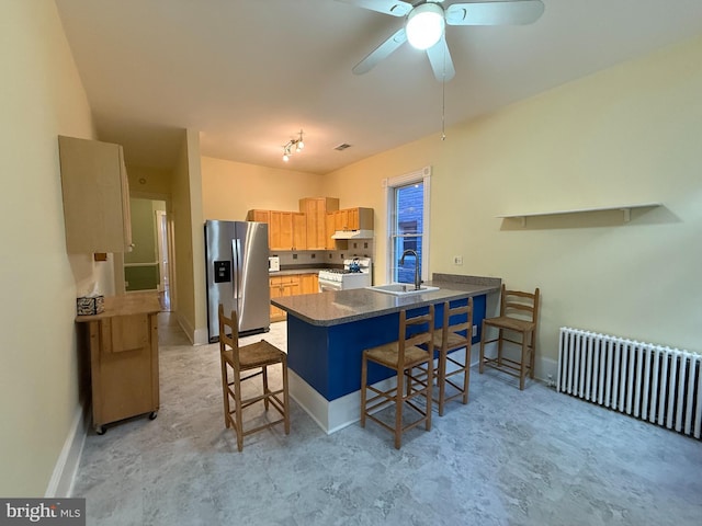 kitchen featuring radiator, sink, stainless steel fridge, kitchen peninsula, and white gas stove