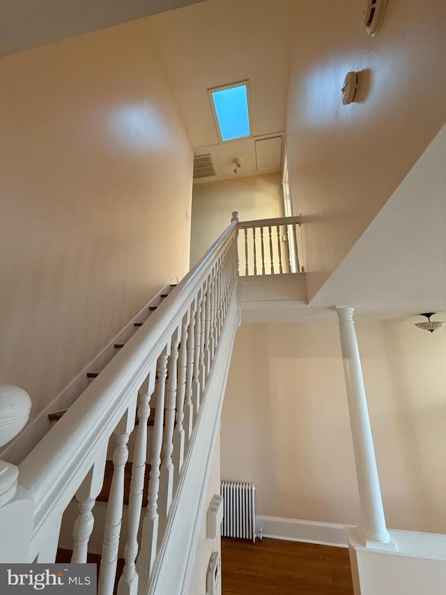 stairs with hardwood / wood-style flooring, radiator, and ornate columns