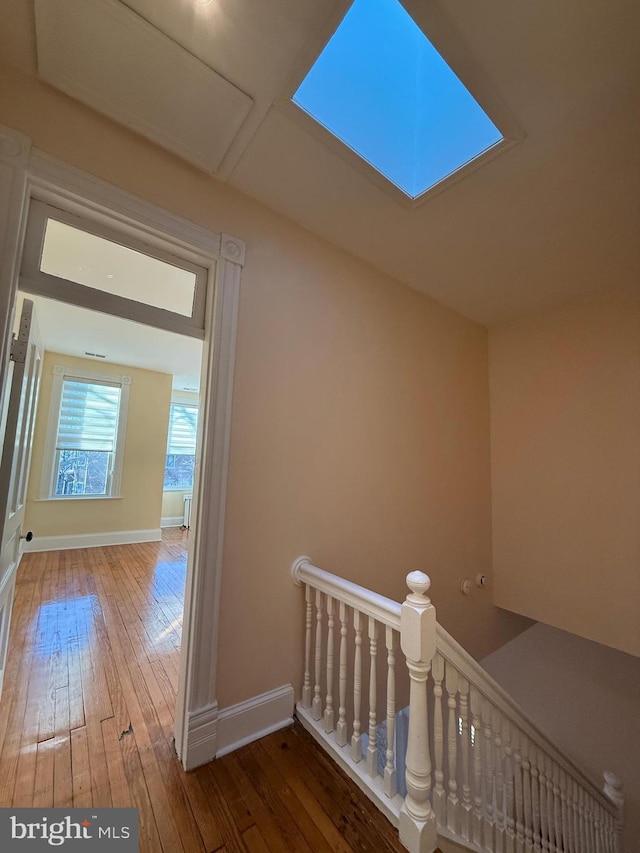 hallway with hardwood / wood-style flooring and a skylight