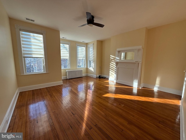 unfurnished living room featuring hardwood / wood-style floors, radiator heating unit, and ceiling fan