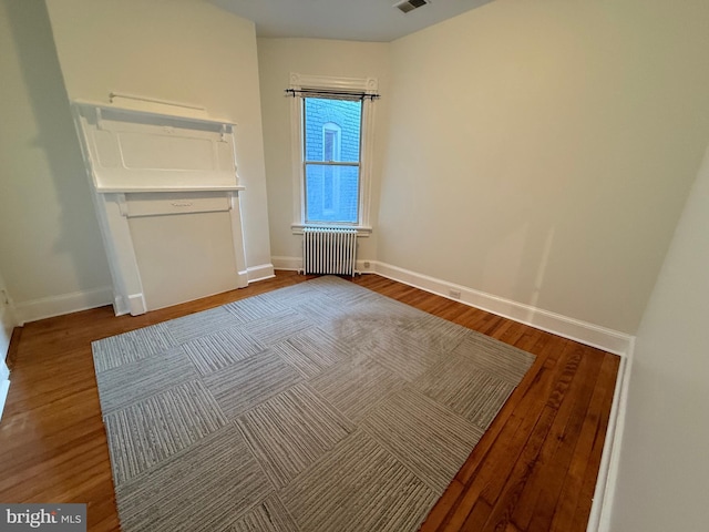 unfurnished room with hardwood / wood-style flooring and radiator heating unit