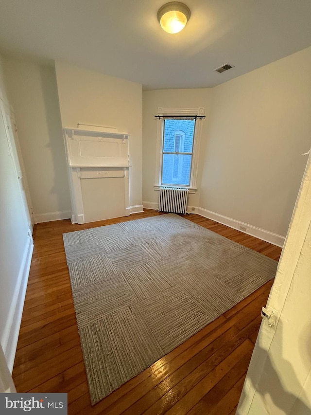 unfurnished bedroom featuring radiator and wood-type flooring