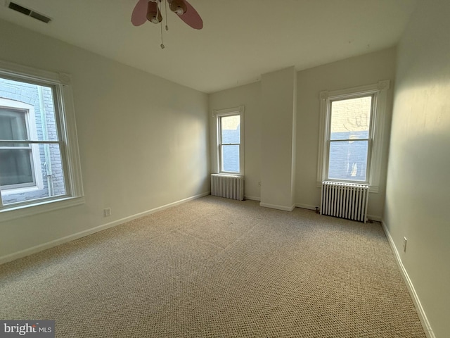 carpeted spare room with radiator heating unit and ceiling fan