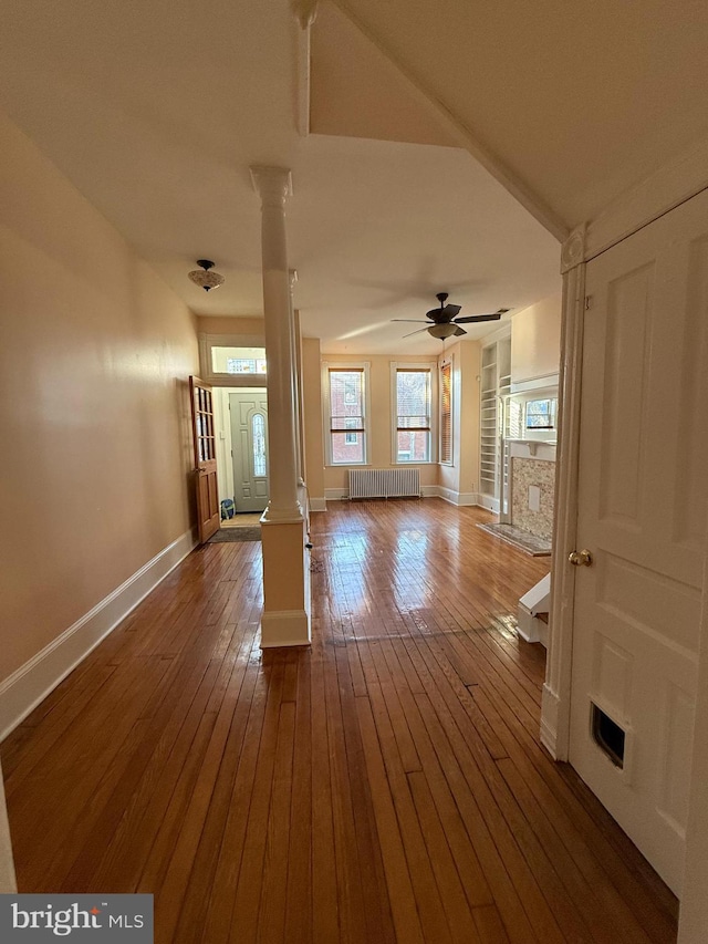 empty room featuring radiator, hardwood / wood-style floors, and ornate columns