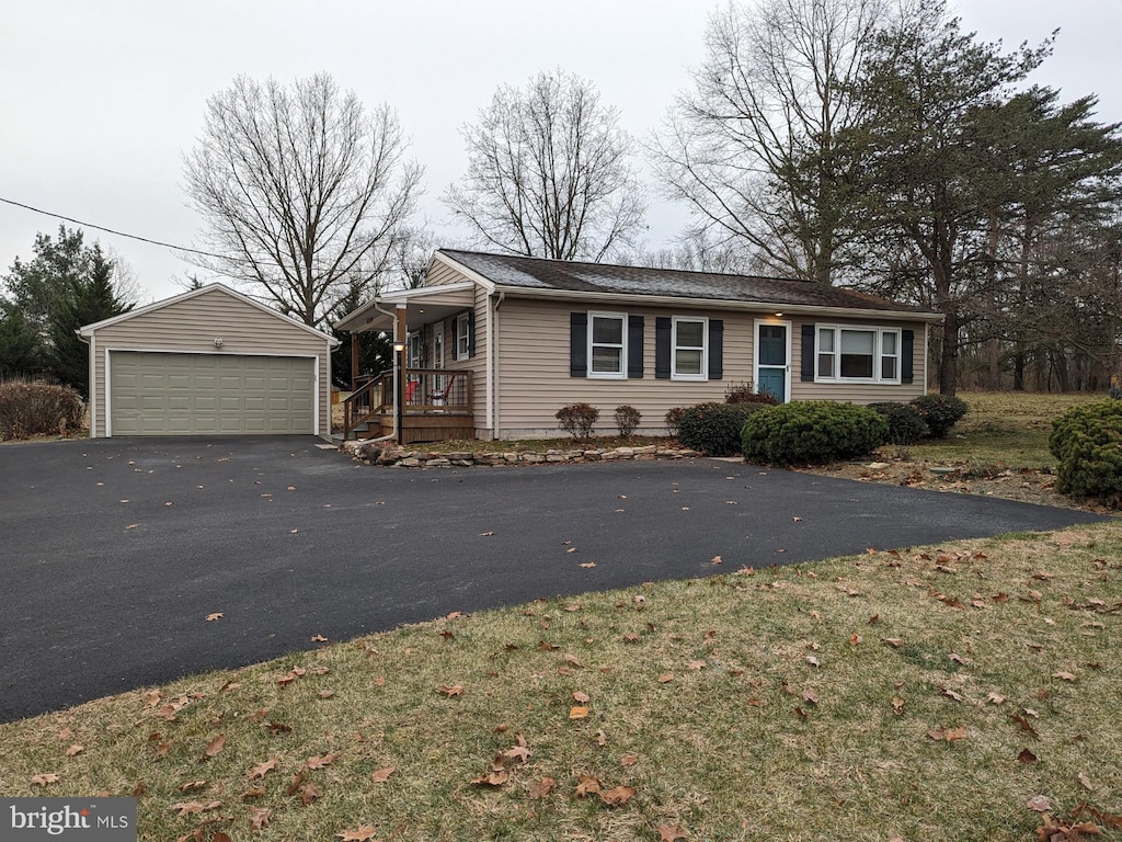 single story home featuring an outbuilding, a garage, and a front lawn