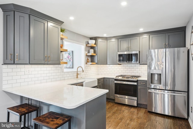 kitchen featuring gray cabinets, appliances with stainless steel finishes, decorative backsplash, and kitchen peninsula