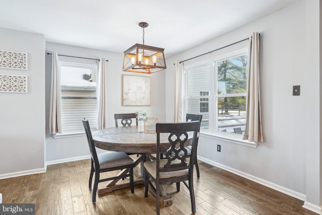 dining room with a notable chandelier, dark wood-type flooring, and a healthy amount of sunlight