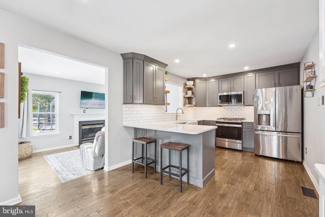 kitchen with a breakfast bar, sink, tasteful backsplash, appliances with stainless steel finishes, and kitchen peninsula