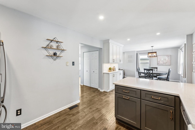 kitchen featuring dark wood-type flooring, dishwasher, white cabinetry, decorative backsplash, and decorative light fixtures