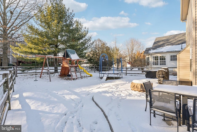 snowy yard with a playground and a trampoline