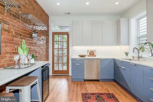 kitchen with a wealth of natural light, brick wall, sink, and stainless steel dishwasher