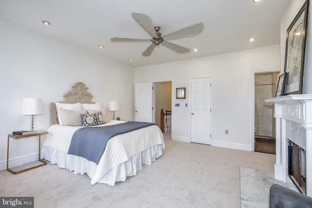 carpeted bedroom featuring a premium fireplace, ceiling fan, and ensuite bathroom