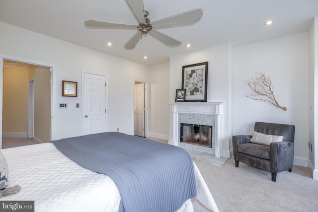 bedroom with a fireplace, light colored carpet, and ceiling fan