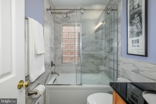 full bathroom featuring vanity, combined bath / shower with glass door, tile walls, and toilet