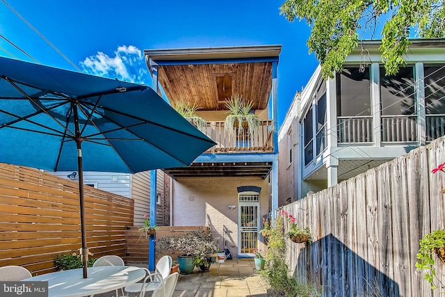 rear view of property with a patio area, a sunroom, and a balcony