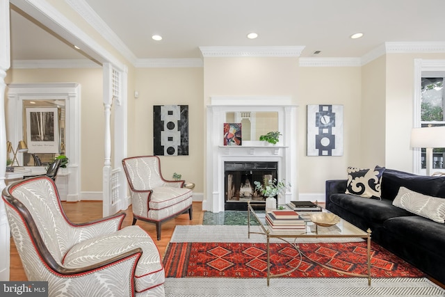 living room featuring crown molding, wood-type flooring, and decorative columns