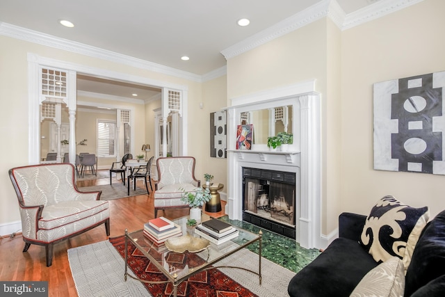 living room featuring hardwood / wood-style floors, crown molding, and decorative columns