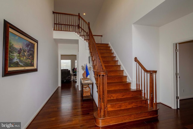 staircase with a high ceiling and hardwood / wood-style floors