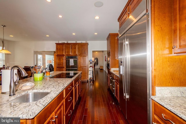 kitchen with dark hardwood / wood-style floors, decorative light fixtures, sink, black appliances, and light stone countertops