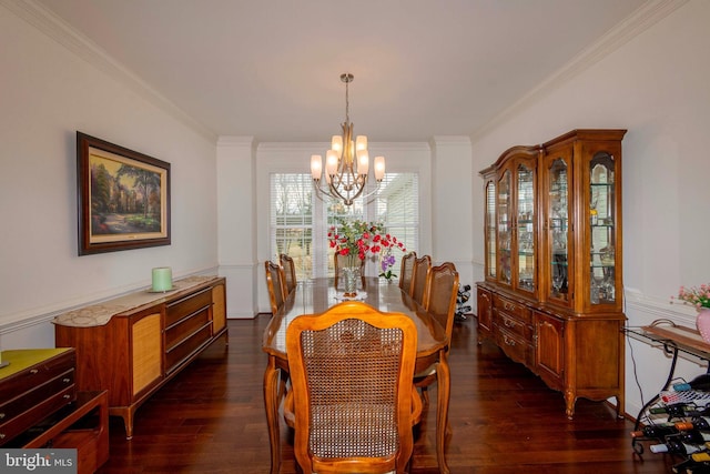 dining room with dark wood-type flooring, ornamental molding, and an inviting chandelier