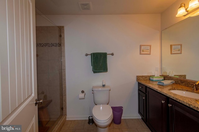 bathroom with vanity, tile patterned floors, toilet, and a tile shower