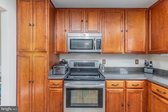 kitchen with dark countertops, brown cabinets, and stainless steel appliances