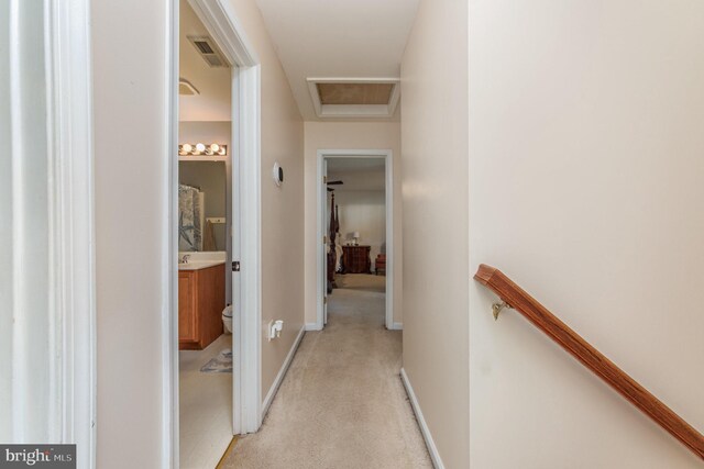 hallway with baseboards, visible vents, attic access, light carpet, and an upstairs landing