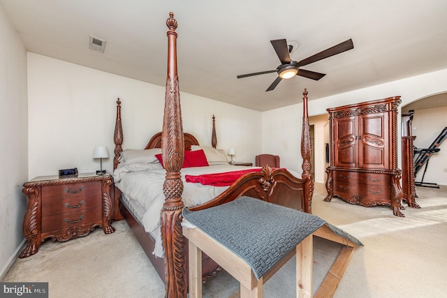 bedroom with light carpet, visible vents, arched walkways, and ceiling fan