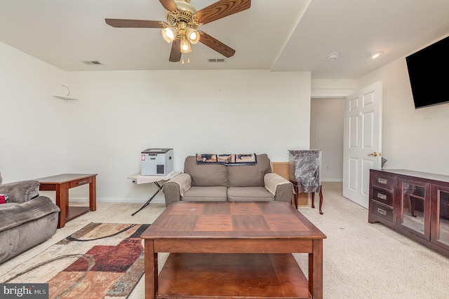 living area with visible vents, baseboards, light colored carpet, and ceiling fan