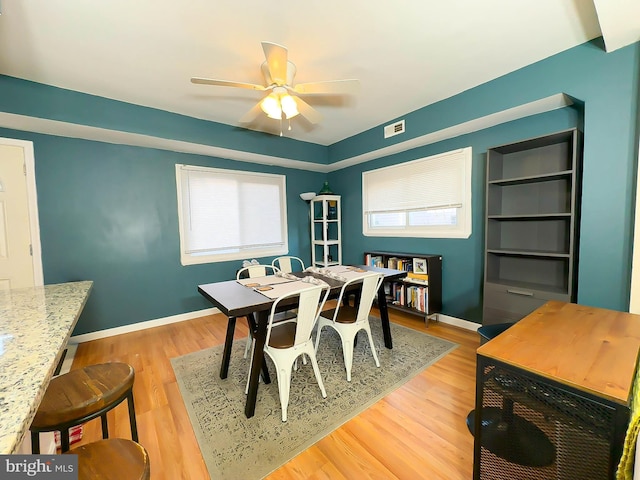 dining area with built in shelves, a wealth of natural light, and light wood-type flooring