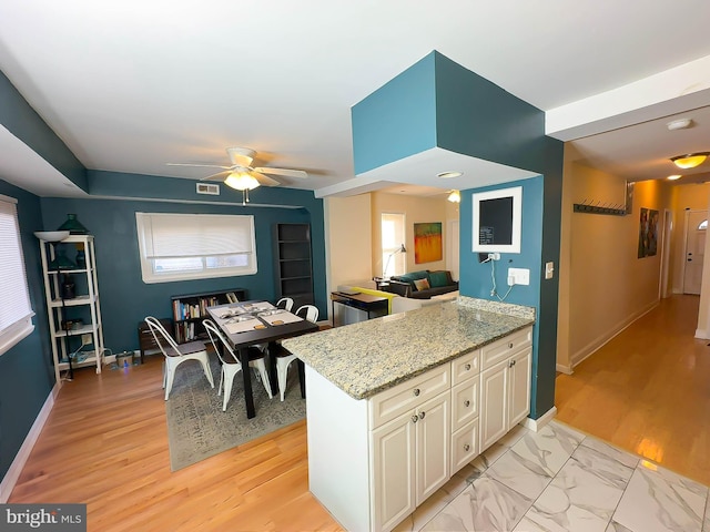 kitchen with light stone countertops and ceiling fan