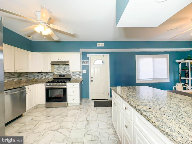 kitchen featuring light stone countertops, white cabinetry, appliances with stainless steel finishes, and tasteful backsplash