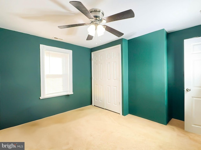 unfurnished bedroom with light carpet, a closet, and ceiling fan