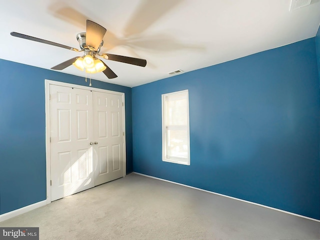 unfurnished bedroom featuring light colored carpet, ceiling fan, and a closet