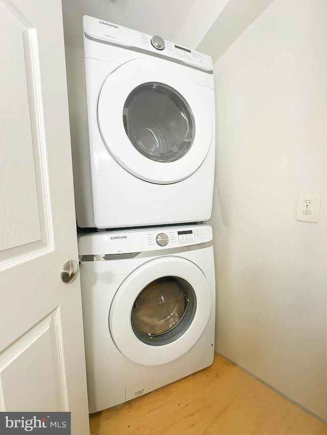 laundry area featuring stacked washer and clothes dryer and light hardwood / wood-style floors