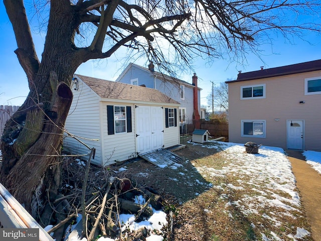 snow covered back of property with an outdoor fire pit