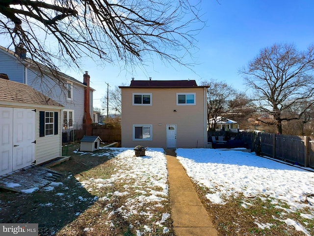 snow covered back of property featuring a storage unit