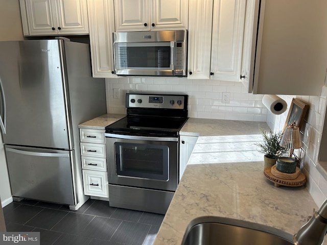 kitchen with appliances with stainless steel finishes, dark tile patterned floors, and backsplash