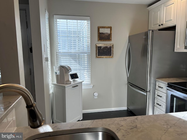 kitchen with white cabinetry, sink, light stone countertops, and stainless steel appliances