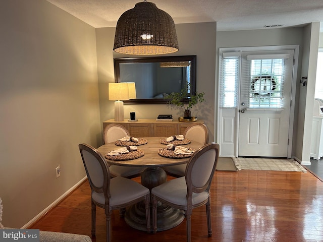 dining room with hardwood / wood-style floors and a textured ceiling