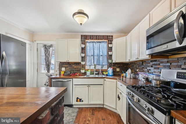 kitchen featuring dark wood-type flooring, sink, tasteful backsplash, wooden counters, and stainless steel appliances