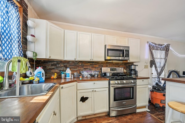 kitchen featuring stainless steel appliances, butcher block counters, sink, and backsplash