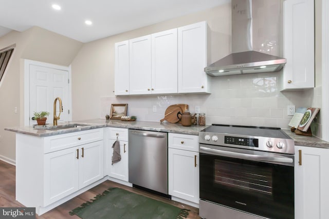 kitchen with sink, white cabinetry, backsplash, stainless steel appliances, and wall chimney exhaust hood